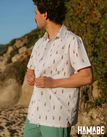 A man wearing a shirt with a surfboard and Hawaiian women pattern from the brand Hamabe.