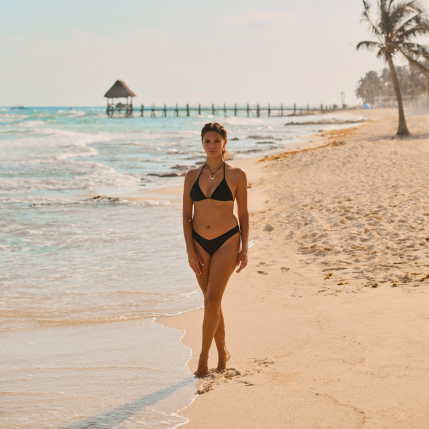 A woman wearing a black bikini on the beach